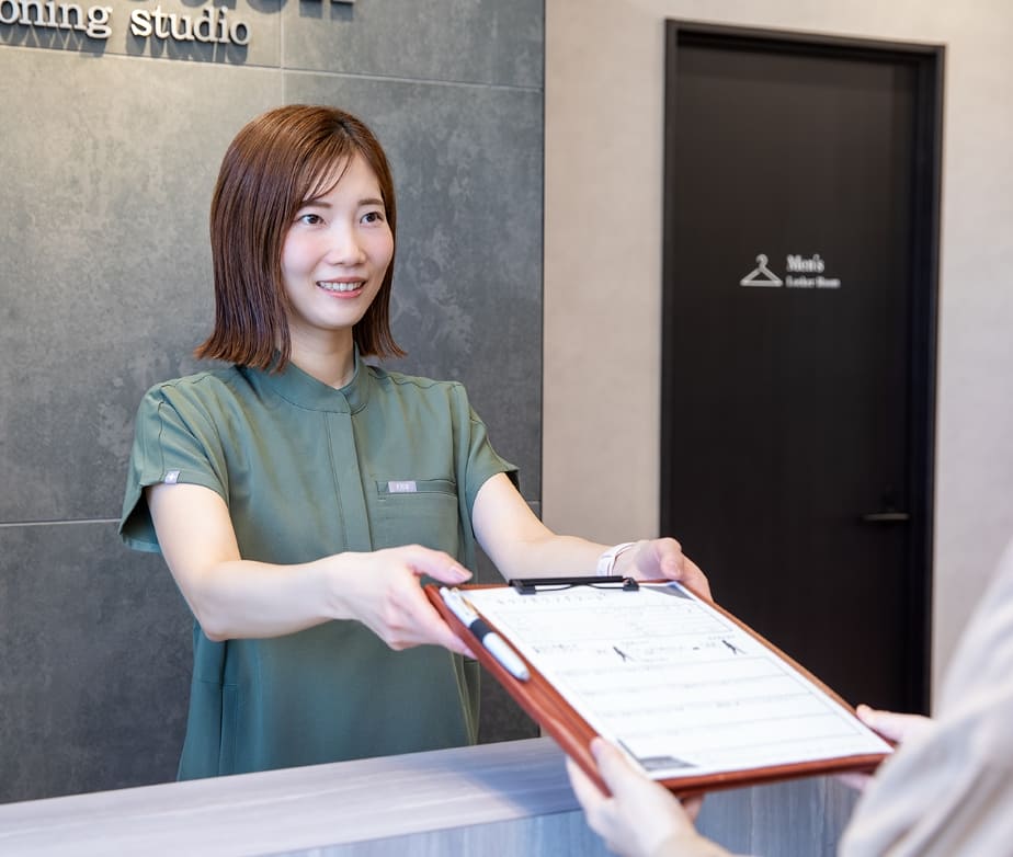 受付でカウンセリングシートを受け取る様子