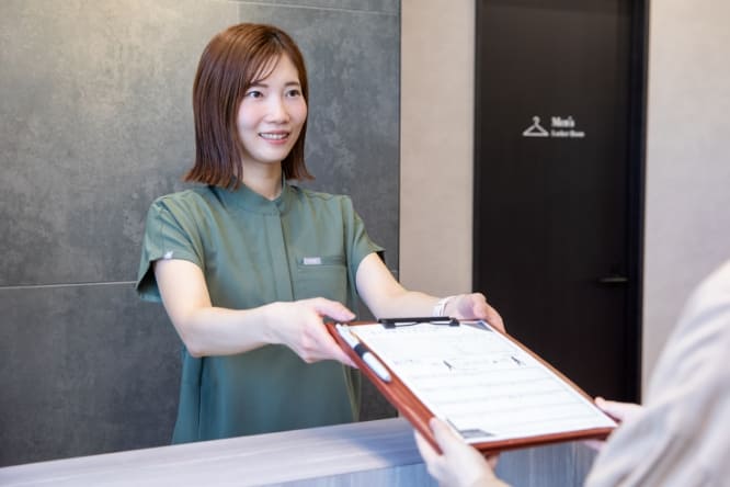 受付でカウンセリングシートを受け取る様子