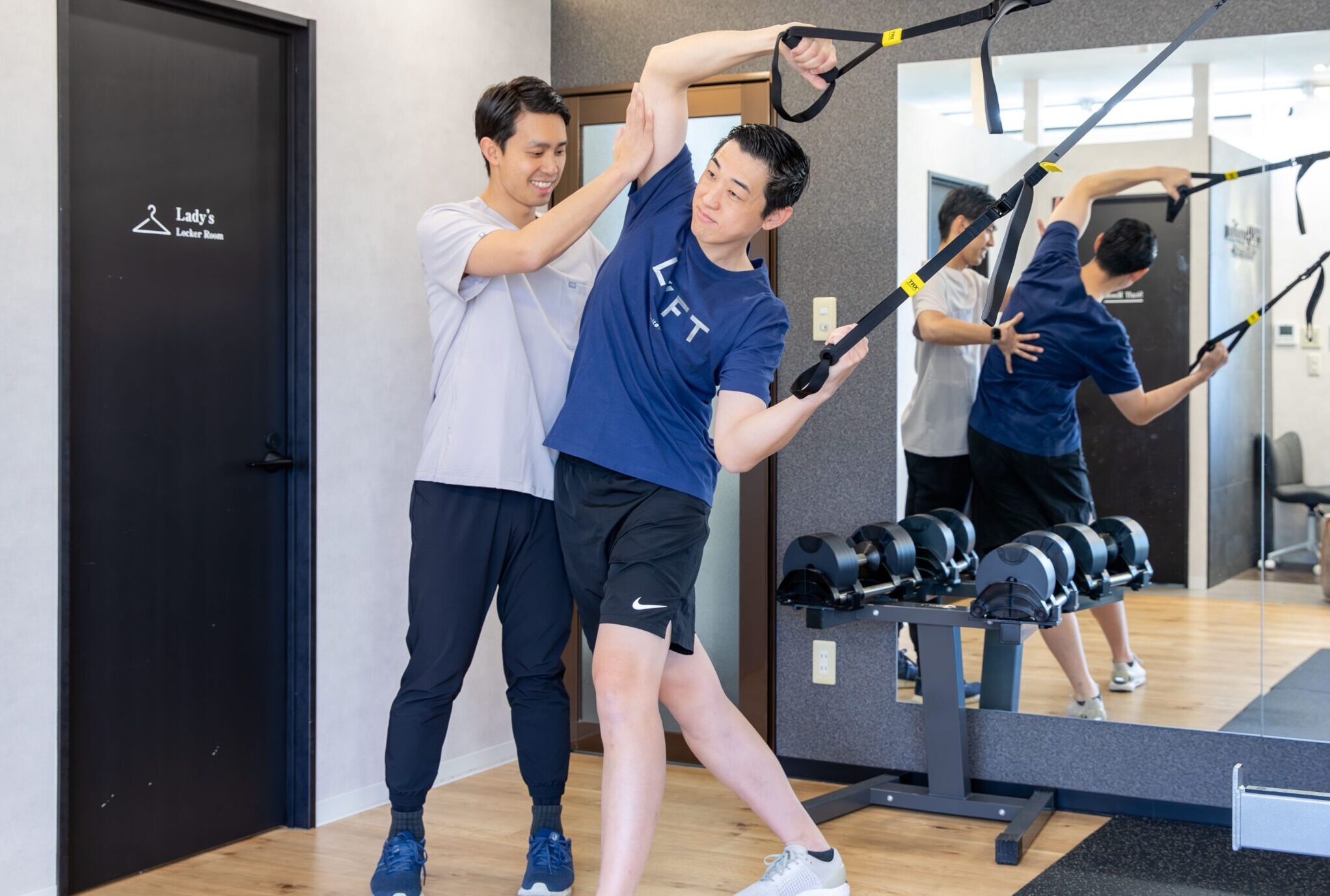 器具を使ってトレーニングを行う男性とサポートするトレーナー