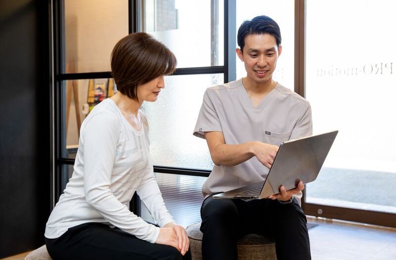 パソコンを指さして説明するトレーナーとそれを見る女性