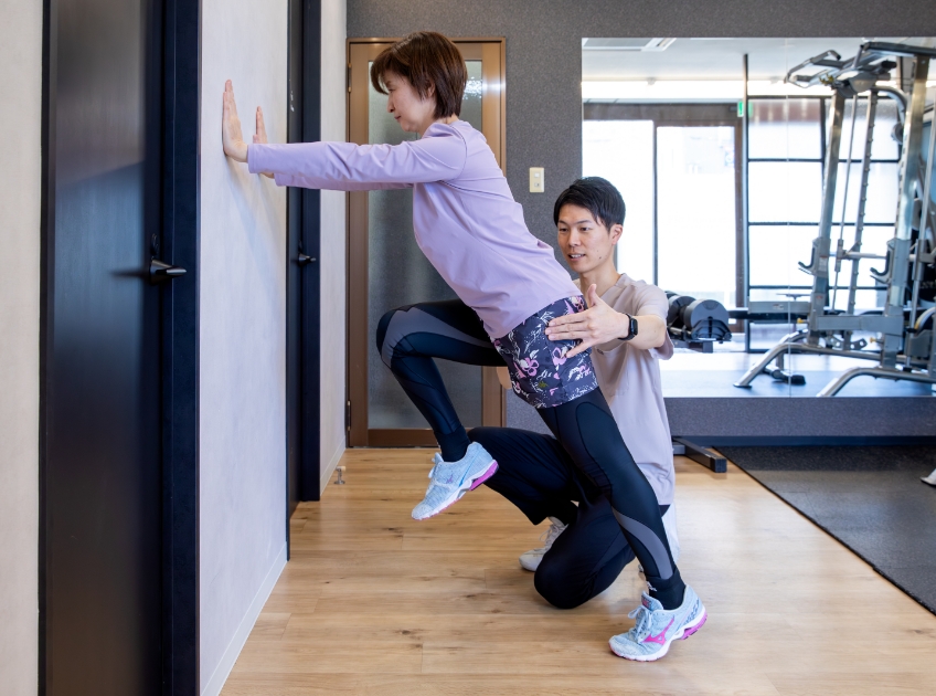 壁に手をつく女性を支えて指示をする男性