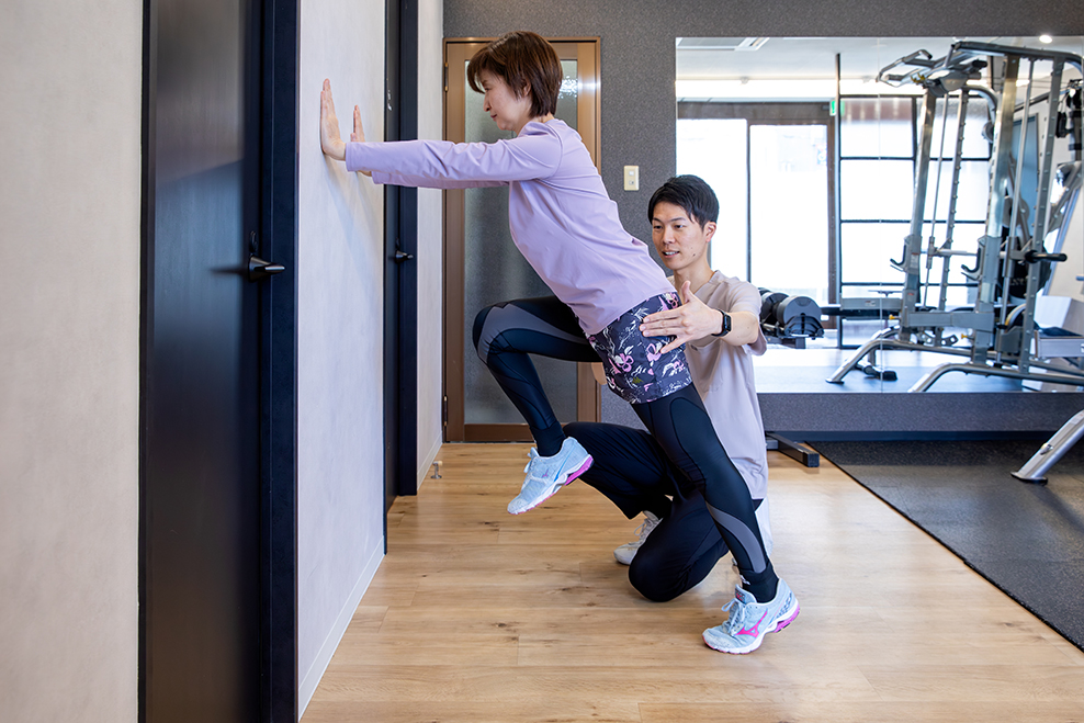 壁に手をつく女性を支えて指示をする男性