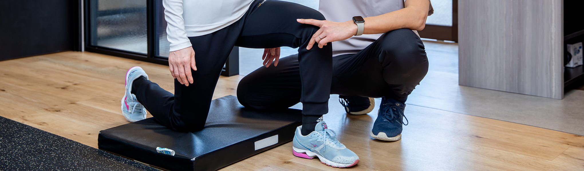 膝のストレッチを指導するトレーナーと指導を受ける女性