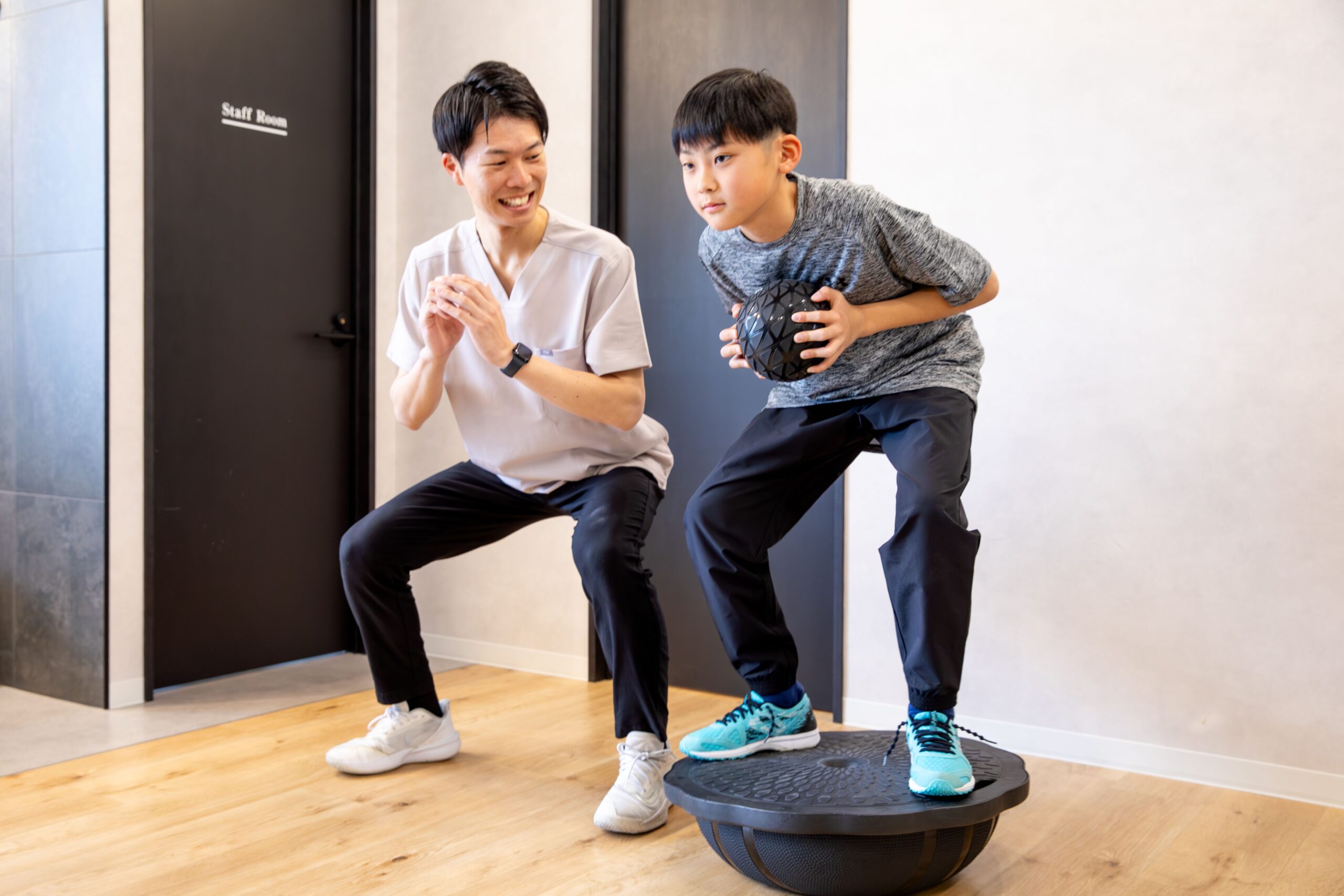 ボールを使ったトレーニングをする男の子とトレーナー