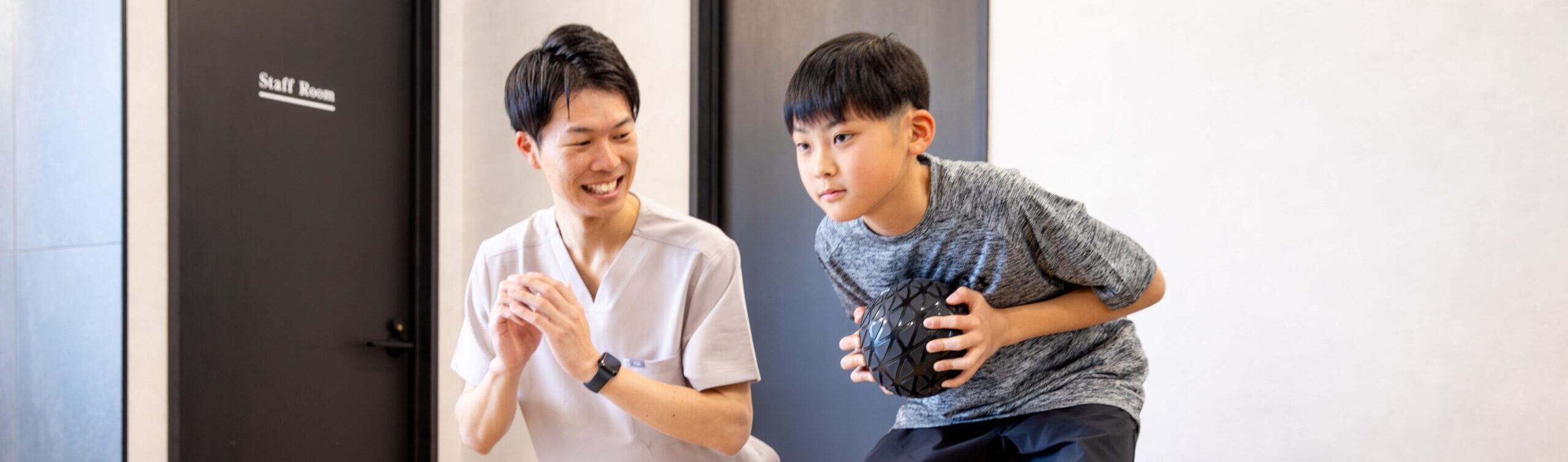 ボールを使ったトレーニングをする男の子とトレーナー