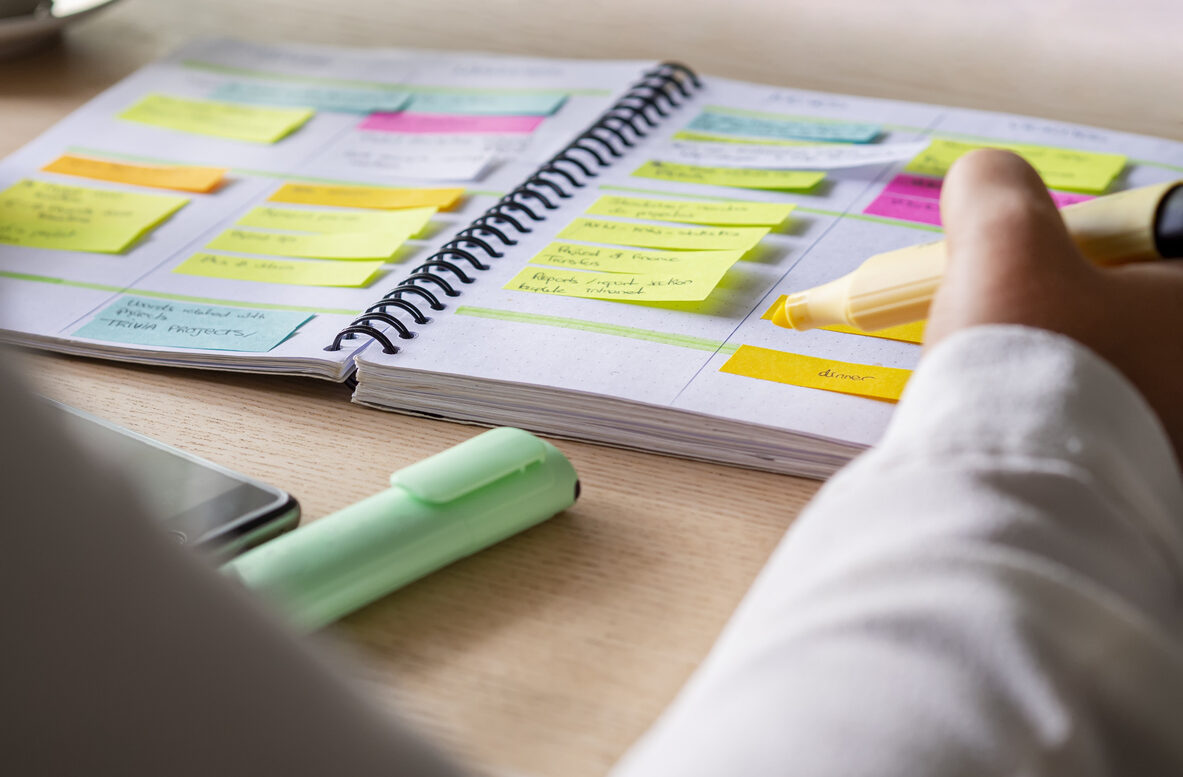 ノートにたくさんの付箋を貼ったり、マーカーを引く手元
