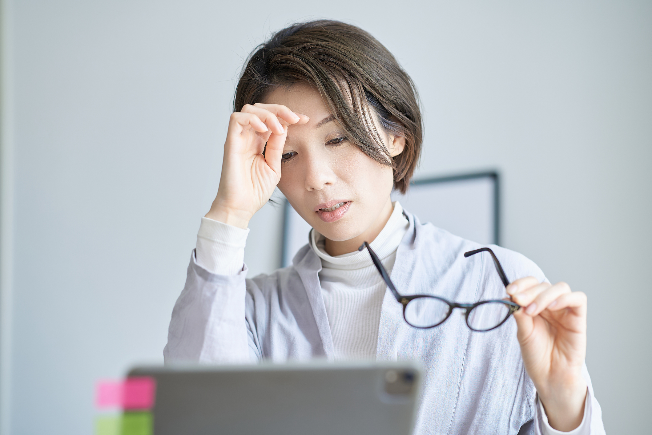 メガネを外して眉間に指を当てる女性